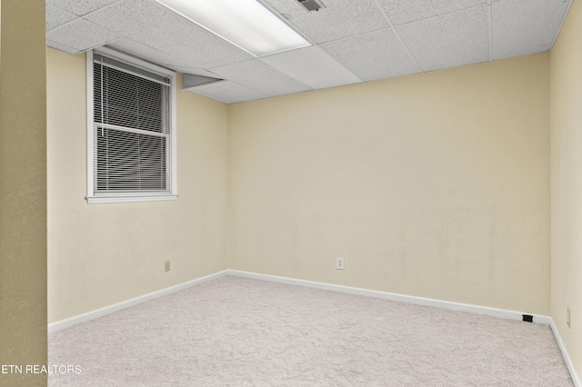 carpeted spare room featuring a drop ceiling