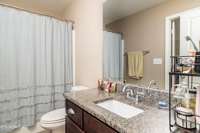 bathroom with curtained shower, vanity, and toilet