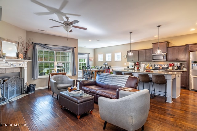 living room with ceiling fan, dark hardwood / wood-style floors, and a tile fireplace