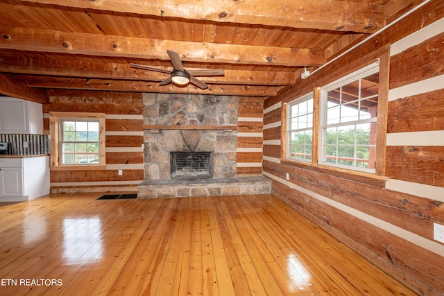 unfurnished living room featuring beam ceiling, light hardwood / wood-style floors, a fireplace, and wood ceiling