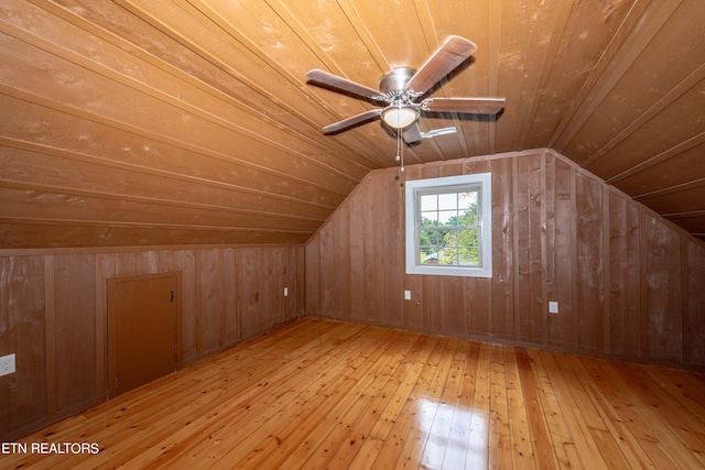 additional living space featuring vaulted ceiling, light wood-type flooring, wooden ceiling, ceiling fan, and wooden walls