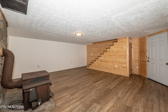 unfurnished living room with hardwood / wood-style flooring, wooden walls, and a textured ceiling