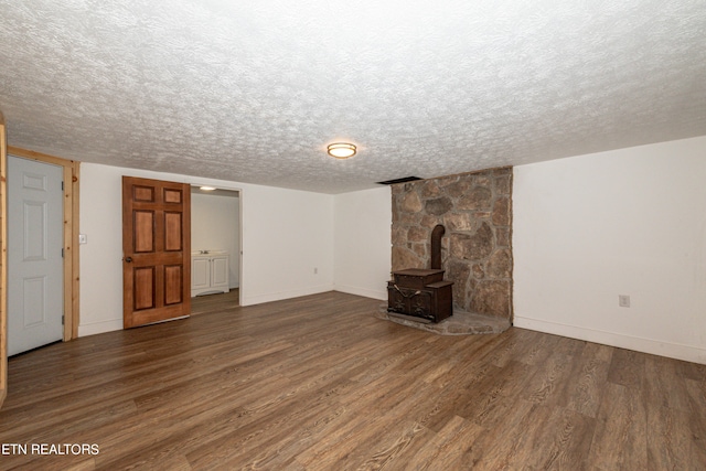 unfurnished living room featuring a textured ceiling, dark wood-type flooring, and a wood stove