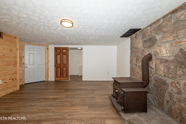 interior space featuring a wood stove, a textured ceiling, and hardwood / wood-style floors