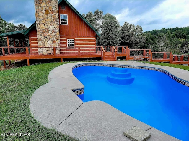 view of swimming pool with a wooden deck and a lawn