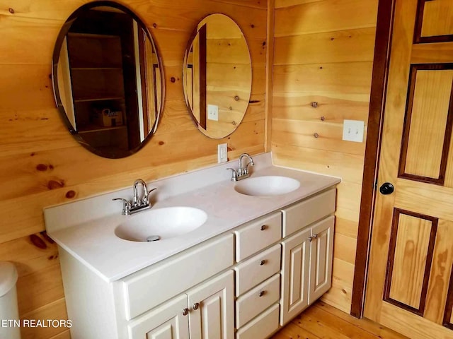 bathroom with wood-type flooring, vanity, and wooden walls