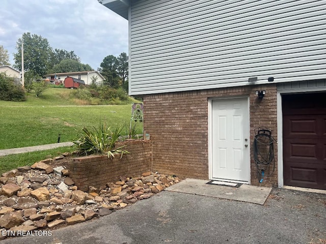 view of exterior entry featuring a yard and a garage