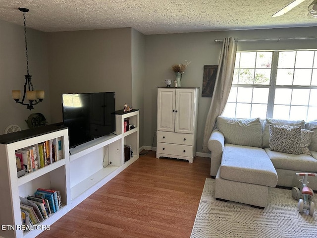 living room featuring a textured ceiling, ceiling fan with notable chandelier, and hardwood / wood-style flooring