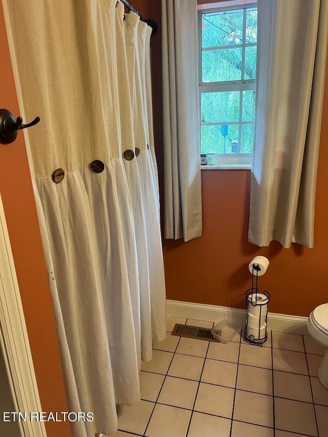 bathroom with walk in shower, toilet, and tile patterned floors