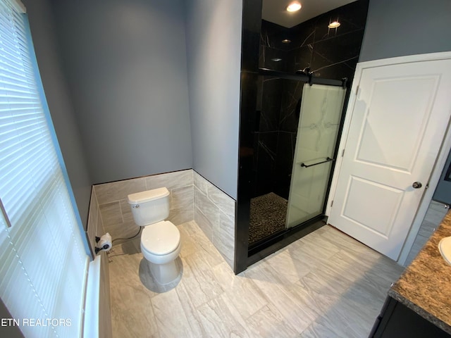 bathroom featuring tiled shower, vanity, toilet, and tile walls