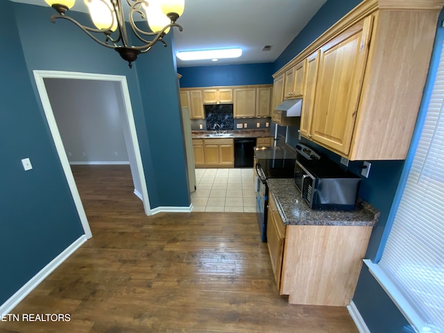 kitchen featuring hardwood / wood-style floors, light brown cabinets, black appliances, sink, and hanging light fixtures