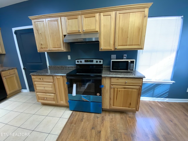 kitchen with dark stone counters, light hardwood / wood-style floors, and black range with electric cooktop