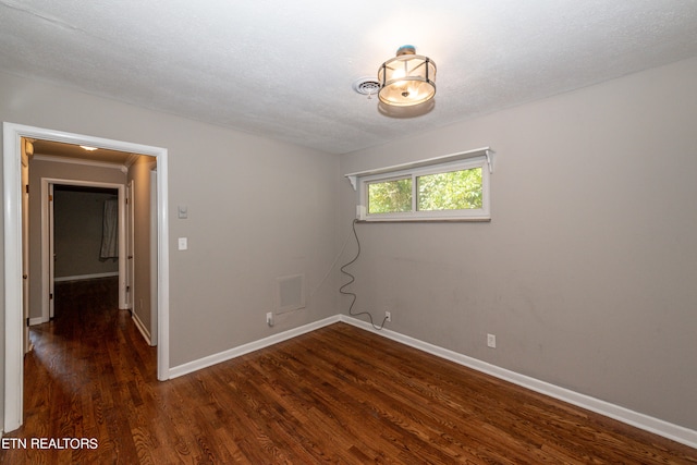 spare room featuring a textured ceiling and dark hardwood / wood-style flooring