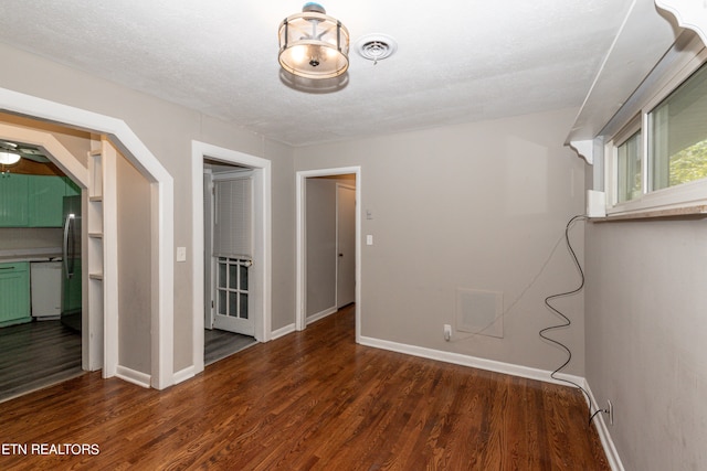 empty room with ceiling fan, a textured ceiling, and dark wood-type flooring