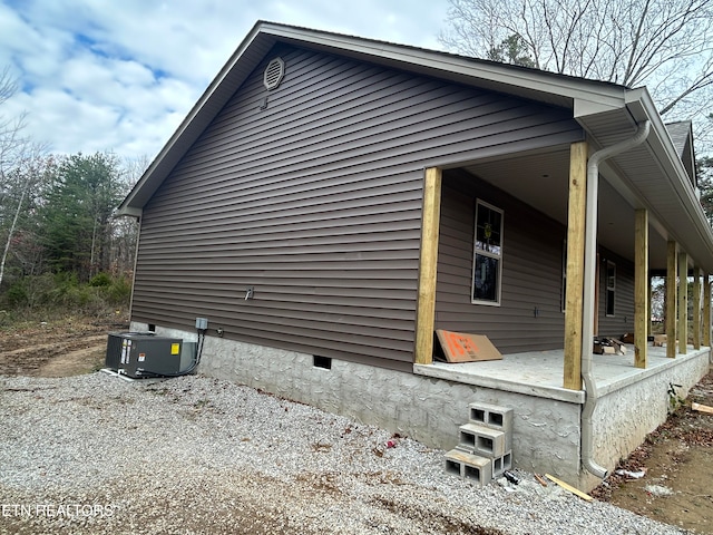 view of side of property featuring covered porch and central air condition unit