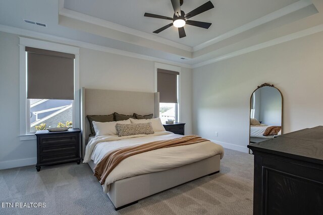 bedroom with crown molding, baseboards, a tray ceiling, and light colored carpet