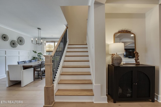 stairs with wood finished floors and a notable chandelier