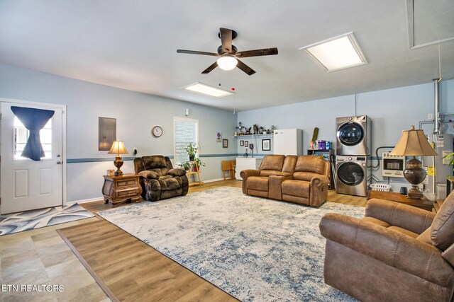 living room featuring ceiling fan, gas water heater, stacked washer and dryer, and a wealth of natural light