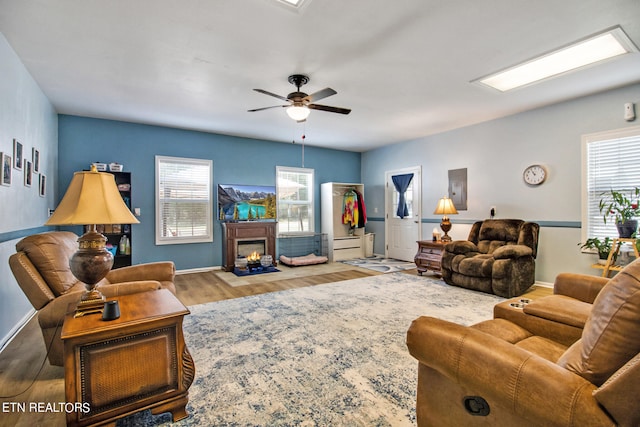 living room featuring wood-type flooring, ceiling fan, and a healthy amount of sunlight