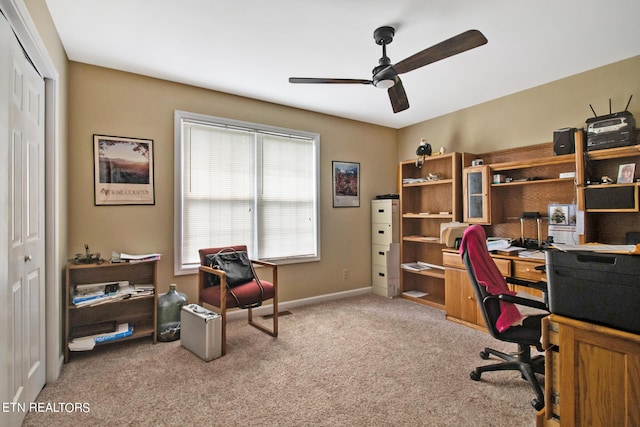 carpeted home office with ceiling fan and baseboards