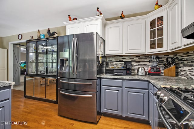 kitchen with gray cabinetry, white cabinets, stainless steel appliances, and light hardwood / wood-style flooring