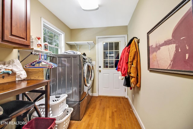 washroom featuring cabinet space, baseboards, light wood finished floors, and separate washer and dryer