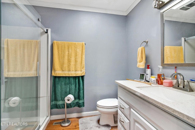 bathroom with vanity, ornamental molding, a stall shower, toilet, and wood finished floors