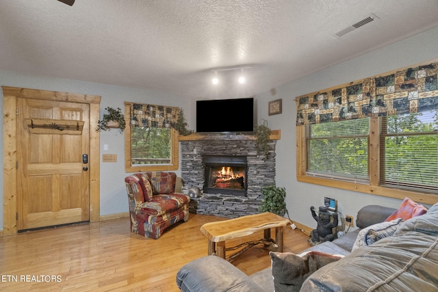 living room with a healthy amount of sunlight, hardwood / wood-style floors, a textured ceiling, and a fireplace