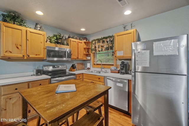 kitchen featuring stainless steel appliances, light brown cabinets, light wood-type flooring, and sink