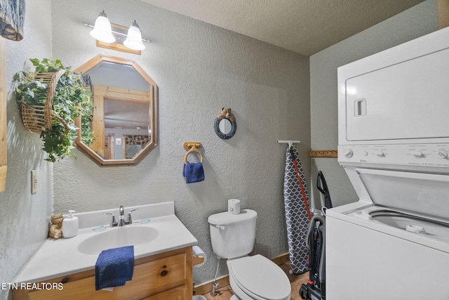 bathroom featuring a textured ceiling, stacked washer and dryer, toilet, and vanity