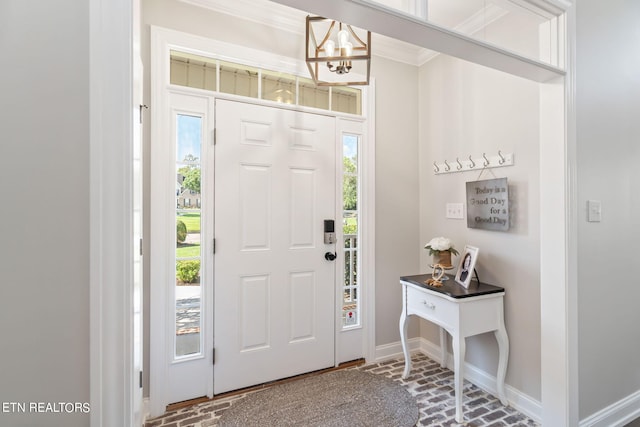 foyer featuring an inviting chandelier and crown molding