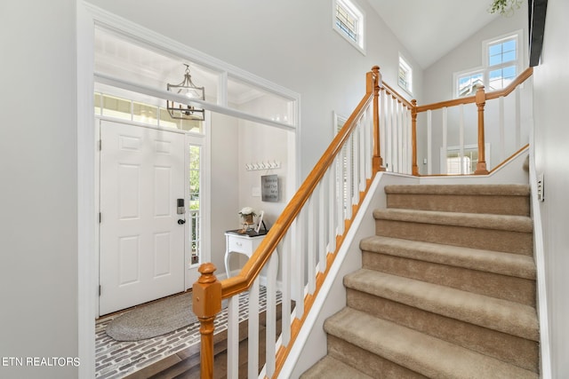 foyer with lofted ceiling, a chandelier, and a wealth of natural light