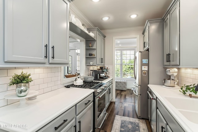 kitchen with ornamental molding, gray cabinetry, backsplash, appliances with stainless steel finishes, and dark hardwood / wood-style flooring