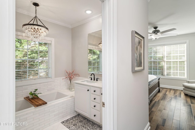 bathroom featuring a wealth of natural light, hardwood / wood-style floors, tiled tub, and vanity