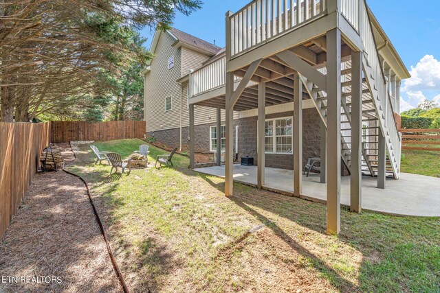 back of house featuring a lawn, a patio, a deck, and an outdoor fire pit