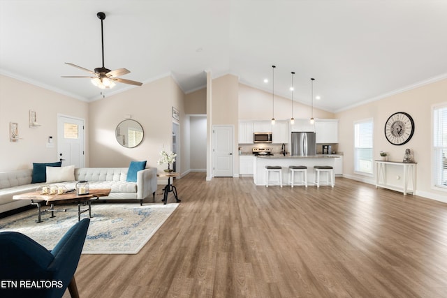 living room featuring ceiling fan, lofted ceiling, crown molding, and light hardwood / wood-style floors