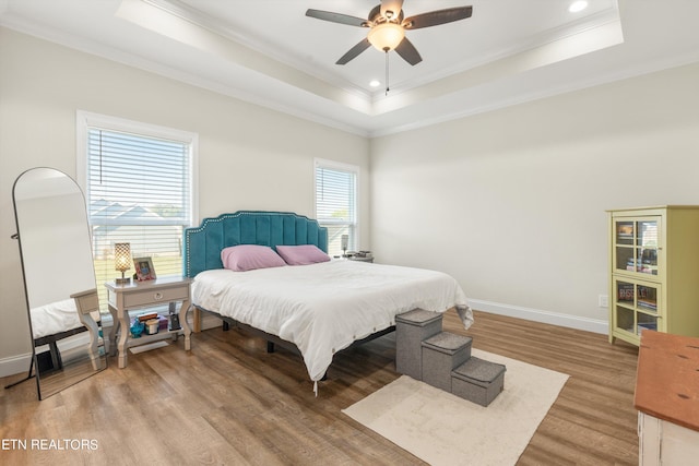 bedroom featuring wood-type flooring, a raised ceiling, crown molding, and ceiling fan