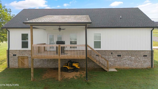 back of property with ceiling fan, a wooden deck, and a lawn