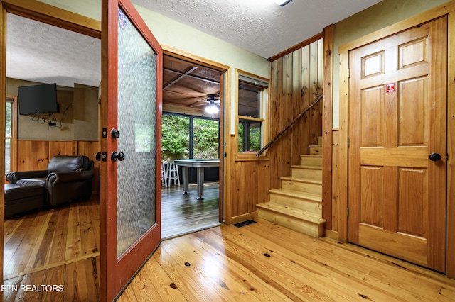 foyer entrance featuring hardwood / wood-style flooring, wooden walls, and a textured ceiling