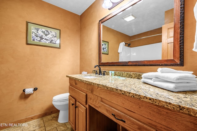 bathroom with a textured ceiling, walk in shower, vanity, and toilet