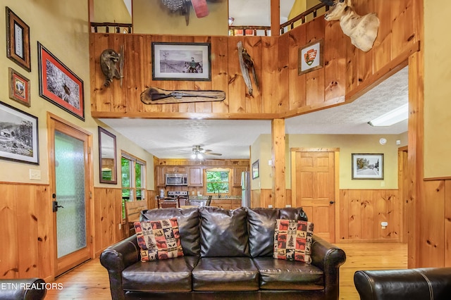 living room with light hardwood / wood-style flooring, wooden walls, ceiling fan, and sink