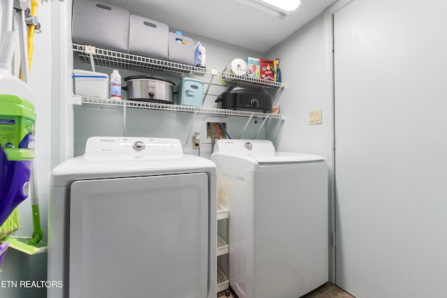 clothes washing area with separate washer and dryer and a textured ceiling