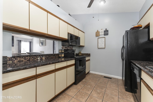 kitchen featuring ceiling fan, dark stone countertops, vaulted ceiling, light tile patterned floors, and black appliances