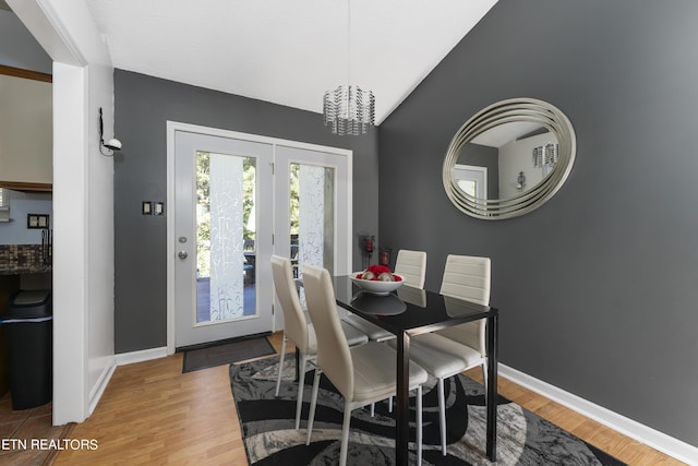 dining space featuring wood-type flooring, vaulted ceiling, and an inviting chandelier