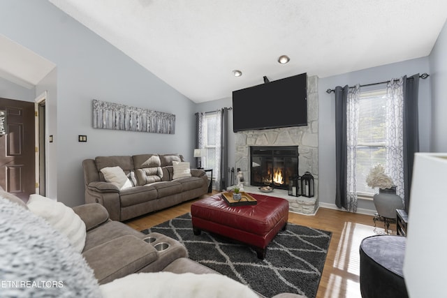 living room with wood-type flooring, lofted ceiling, a fireplace, and a wealth of natural light