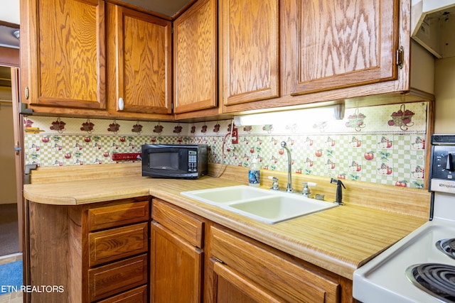 kitchen featuring decorative backsplash, stove, and sink