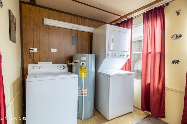 laundry area with gas water heater, wood walls, light tile patterned floors, and stacked washer / dryer