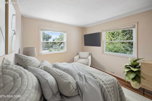 bedroom with crown molding, multiple windows, and hardwood / wood-style floors