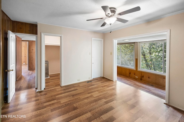 unfurnished bedroom featuring ceiling fan, wood walls, wood-type flooring, and a textured ceiling