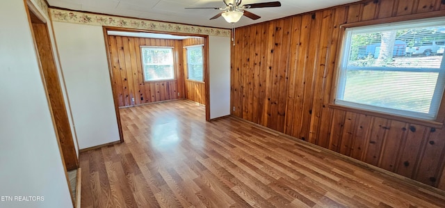 unfurnished room with ceiling fan, wood-type flooring, and wood walls